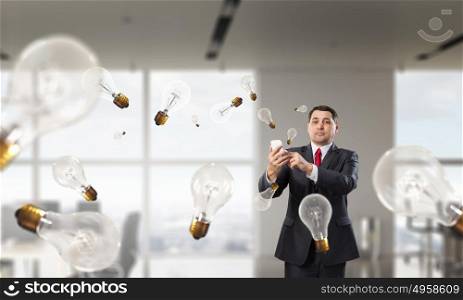 Businessman with mobile phone in hand. Adult businessman in modern office interior using mobile phone