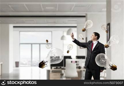 Businessman with mobile phone in hand. Adult businessman in modern office interior using mobile phone