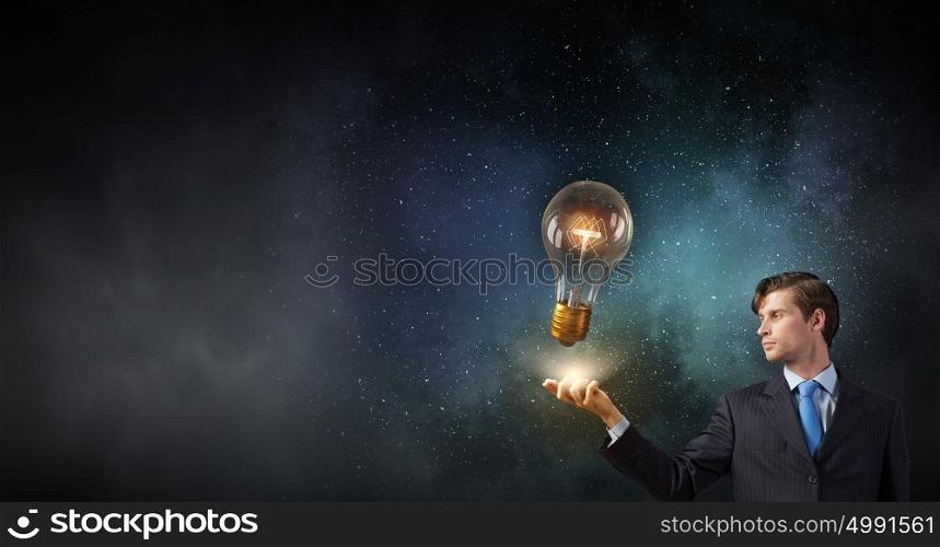 Businessman with mobile phone. Young businessman with mobile phone in hand looking at glass lightbulb