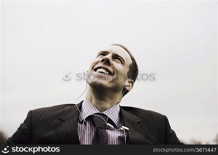 Businessman with MP3 player looks up smiling