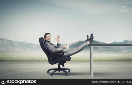 Businessman with mug. Young confident businessman sitting in chair with mug in hands