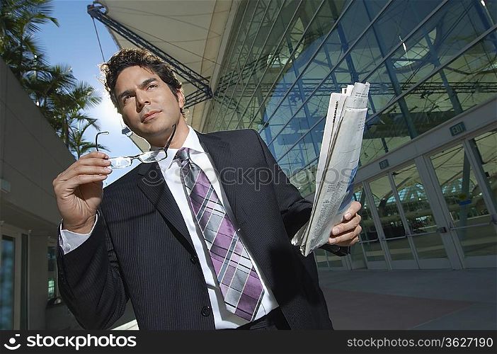 Businessman with newspaper outside office building