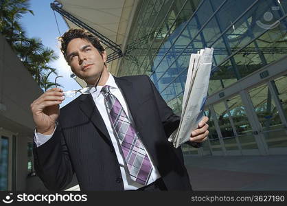 Businessman with newspaper outside office building