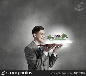 Businessman with opened book. Businessman holding opened book with construction model on pages