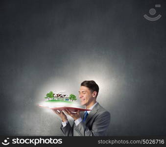 Businessman with opened book. Businessman holding opened book with construction model on pages
