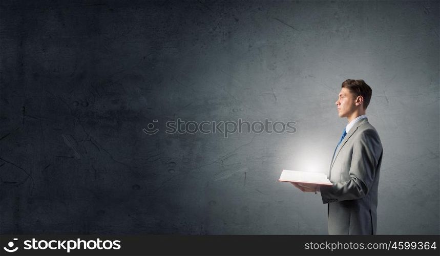 Businessman with opened book. young businessman holding opened book and light on pages