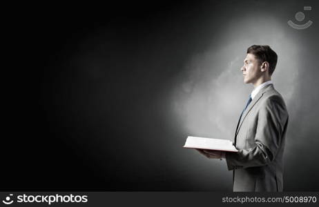 Businessman with opened book. young businessman holding opened book and light on pages