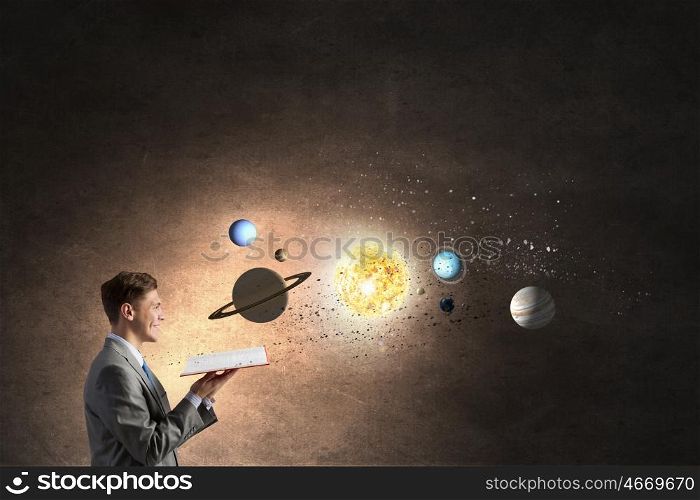 Businessman with opened book. Young businessman with book and planets of space spinning around