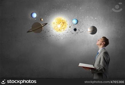 Businessman with opened book. Young businessman with book and planets of space spinning around