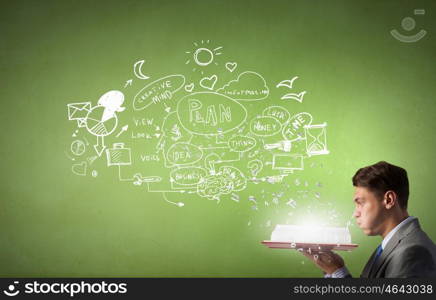 Businessman with opened book. Young businessman with opened book and plan sketches from pages