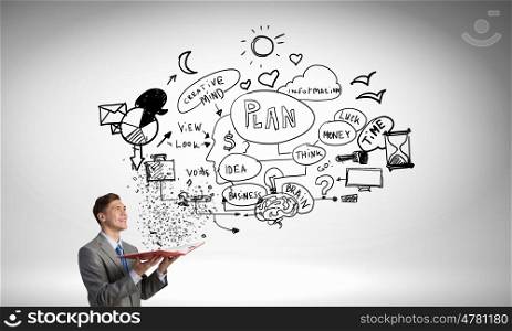 Businessman with opened book. Young businessman with opened book and plan sketches from pages
