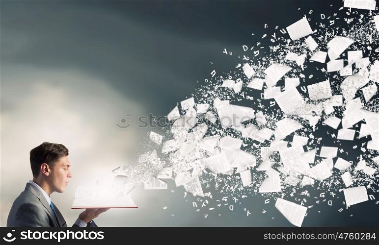 Businessman with opened book. Young businessman with opened book in hands and pages flying in air