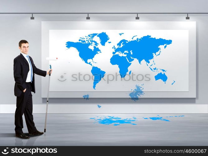 Businessman with paint brush and world map on the background