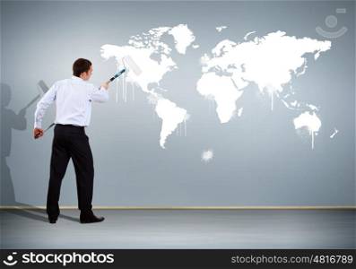 Businessman with paint brush and world map on the background