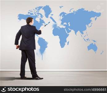 Businessman with paint brush and world map on the background