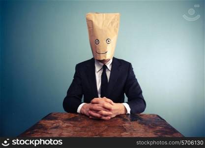 Businessman with paper bag over his head at desk