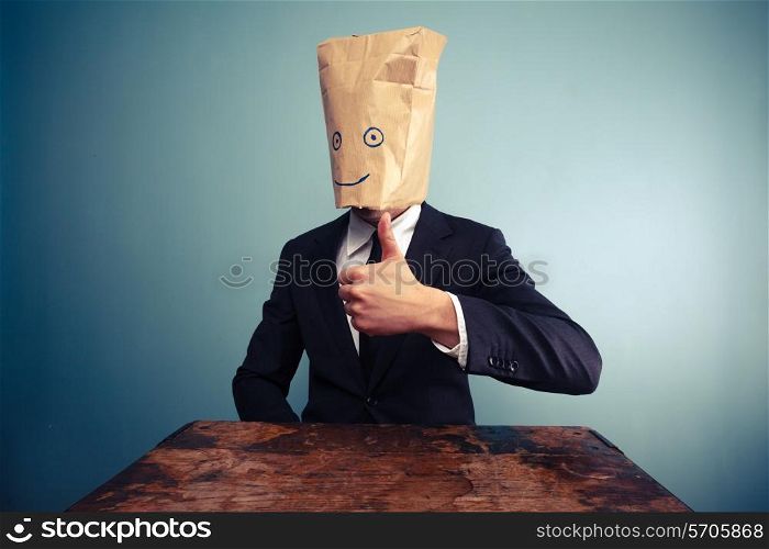 Businessman with paper bag over his head giving thumb up