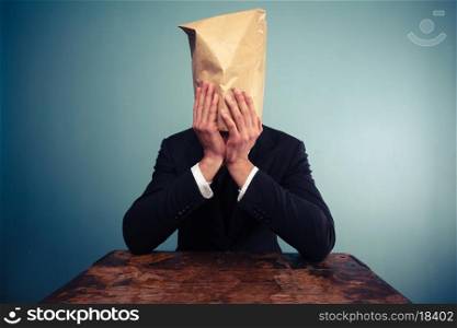 Businessman with paper bag over his head in despair