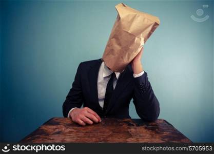 Businessman with paper bag over his head is sad