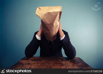 Businessman with paper bag over his head is very sad