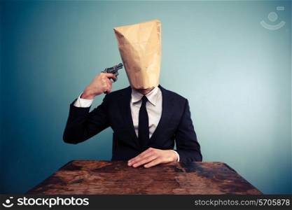 Businessman with paper bag over his head putting gun to his head