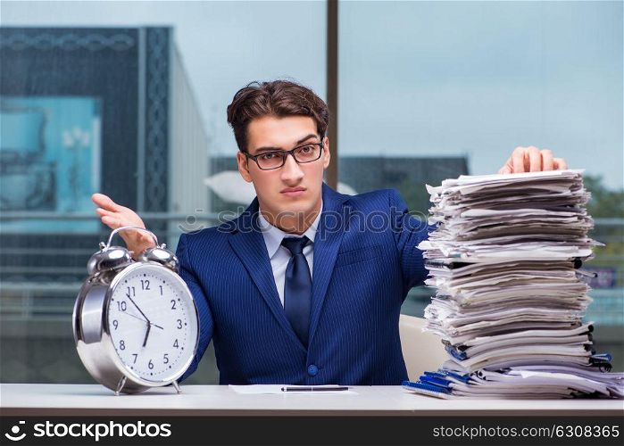 Businessman with pile stack of paper paperwork and an alarm cloc. Businessman with pile stack of paper paperwork and an alarm clock working in the office