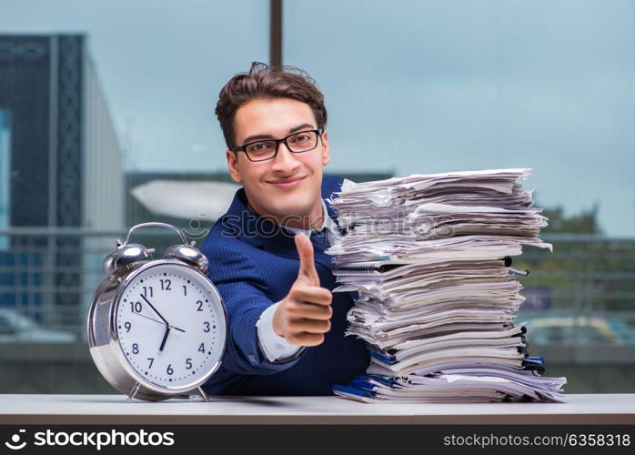 Businessman with pile stack of paper paperwork and an alarm cloc. Businessman with pile stack of paper paperwork and an alarm clock working in the office