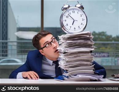 Businessman with pile stack of paper paperwork and an alarm clock working in the office. Businessman with pile stack of paper paperwork and an alarm cloc