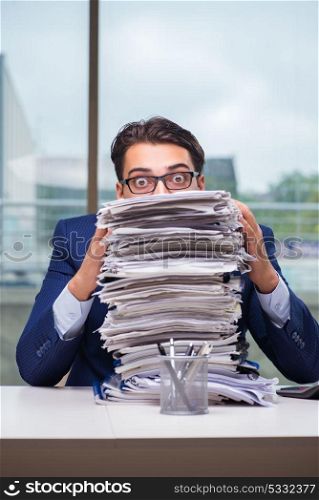 Businessman with pile stack of paper paperwork in the office