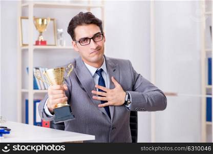 Businessman with prize cup for achievements in office