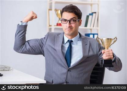 Businessman with prize cup for achievements in office