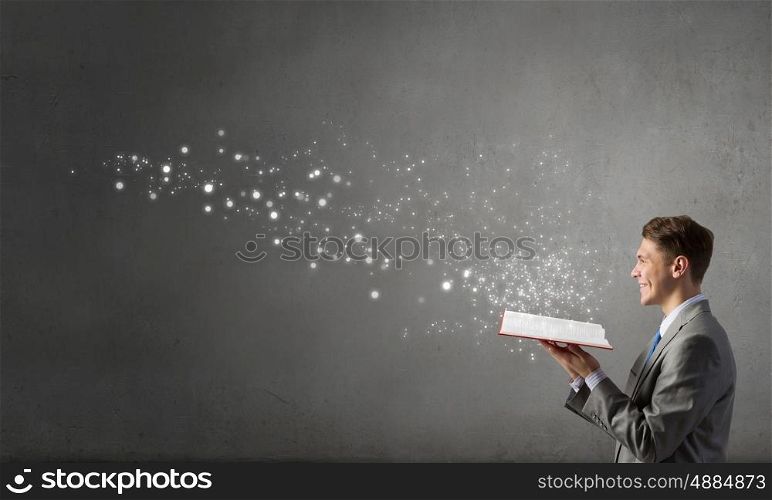 Businessman with red book. Smiling businessman in suit holding red opened book