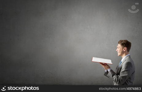 Businessman with red book. Smiling businessman in suit holding red opened book