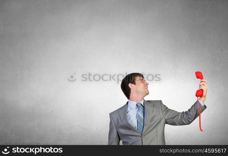 Businessman with red receiver. Handsome businessman talking on red phone handset