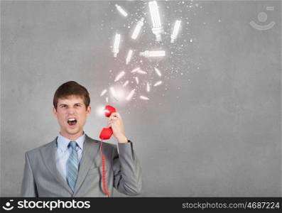 Businessman with red receiver. Handsome businessman talking on red phone handset