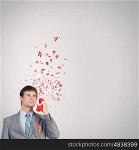 Businessman with red receiver. Handsome businessman talking on red phone handset