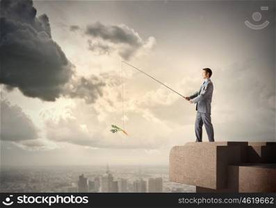 Businessman with rod. Young businessman standing on top of building and fishing