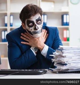 Businessman with scary face mask working in office. Businessmsn with scary face mask working in office