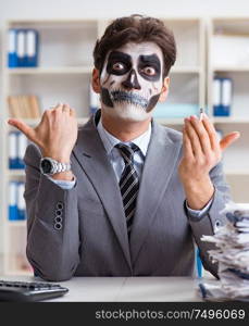 Businessman with scary face mask working in office. Businessmsn with scary face mask working in office