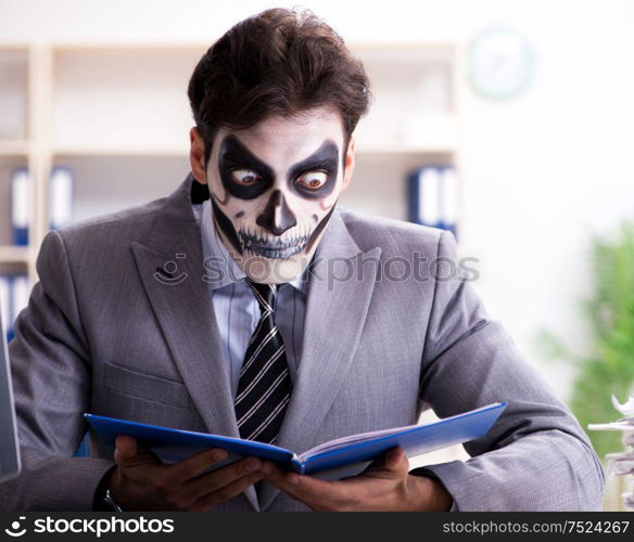 Businessman with scary face mask working in office. Businessmsn with scary face mask working in office