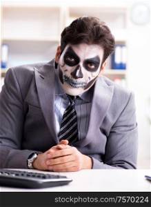 Businessman with scary face mask working in office. Businessmsn with scary face mask working in office