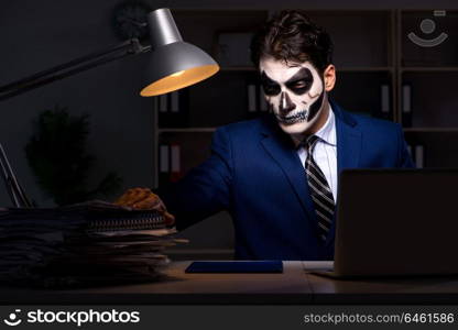 Businessman with scary face mask working late in office