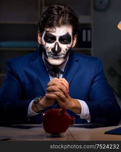 Businessman with scary face mask working late in office. The businessman with scary face mask working late in office