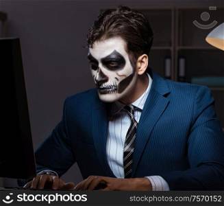 Businessman with scary face mask working late in office. The businessman with scary face mask working late in office