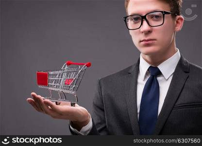 Businessman with shopping cart on gray background
