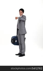 Businessman with suitcase looking at wrist watch