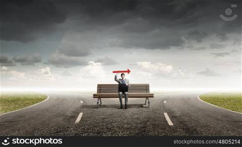 Businessman with suitcase. Young smiling businessman sitting on bench with briefcase in hands