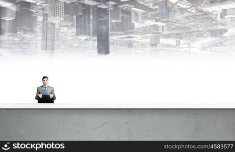 Businessman with suitcase. Young smiling businessman sitting with briefcase in hands