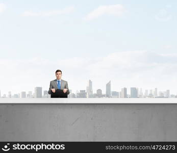 Businessman with suitcase. Young smiling businessman sitting with briefcase in hands