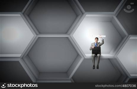 Businessman with suitcase. Young smiling businessman sitting with briefcase in hands